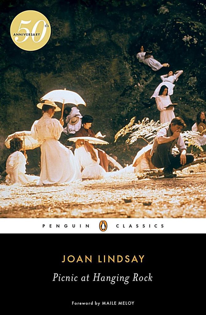 Picnic at Hanging Rock by Joan Lindsay, a penguin classics cover consisting of a group of Victorian era girls scattered outside.
