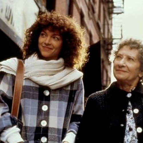 Two women outside of a city apartment brown stone bundled in warm weather cloths.