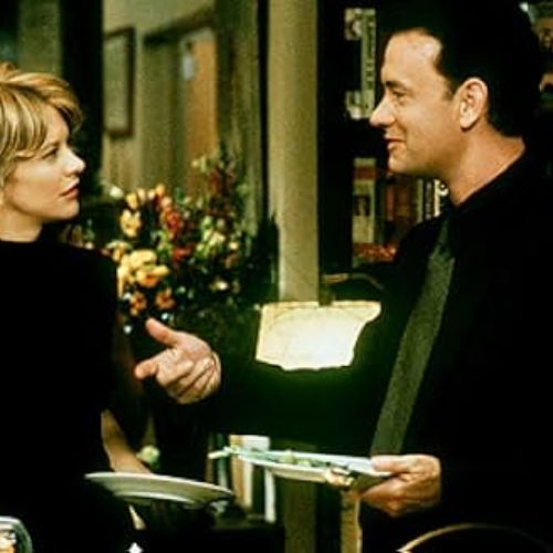 Meg Ryan and Tom Hanks talking while holding plates during a party.