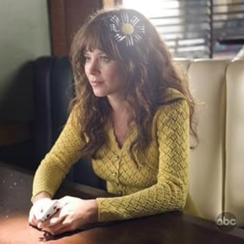 TV still from Pushing Daisies, featuring the character Chuck, wearing a yellow top sitting at a table.