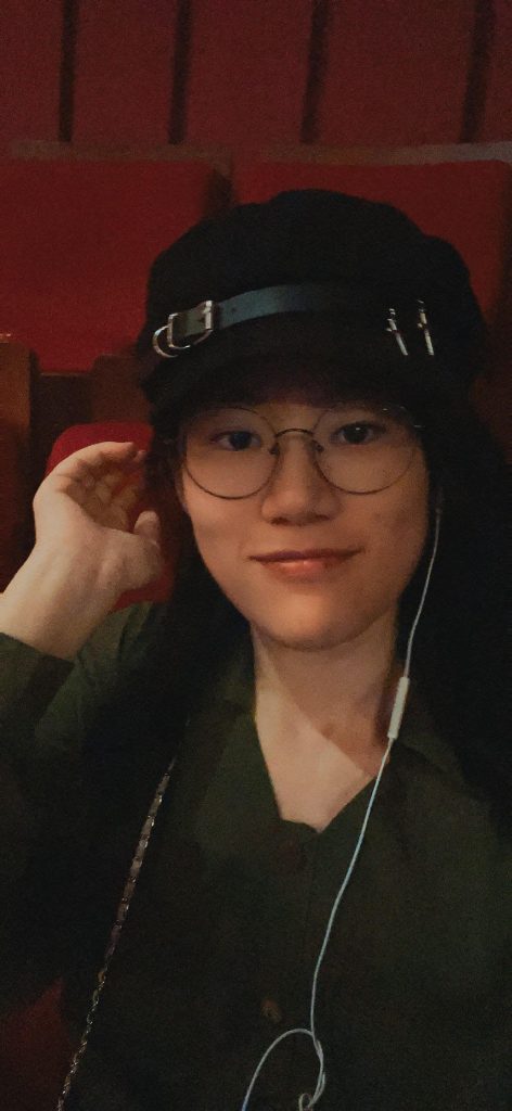 Sapphic, queer author Dawn Chen sitting in movie theatre seats.