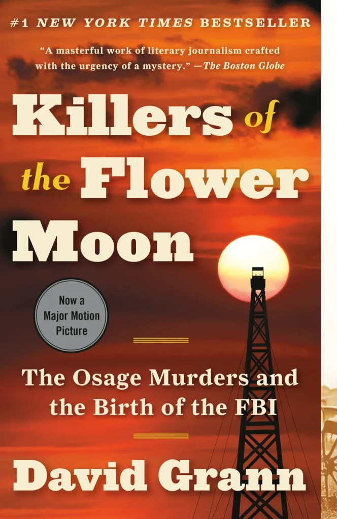 Killers of the Flower Moon by David Grann book cover depicts an orange sky with the top of an oil rig in front of a large moon.