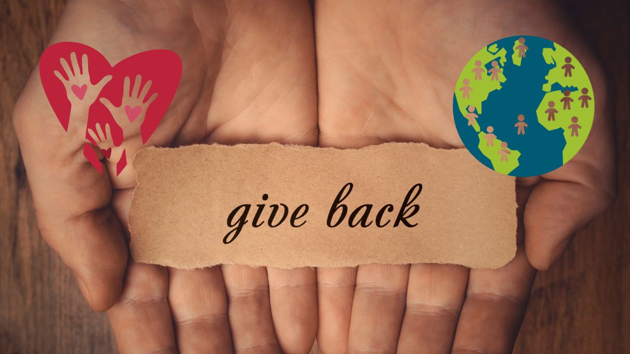Depicts opened hands with a sign saying 'give back' with a heart with hands cut out and an earth with people cut out.
