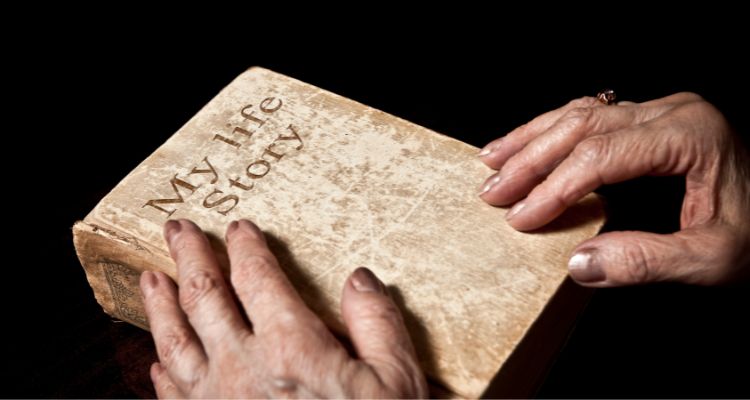 This image features a weathered book with the words "My Life Story on the outside, with hands grasping the sides of it.