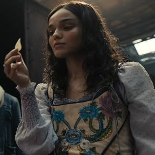 Movie still of Lucy Gray Baird in The Ballad of Songbirds and Snakes holding up a single white rose petal.