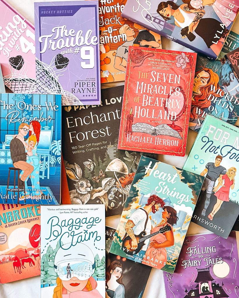 Flatlay post made by Bookstagrammer Britt of romance novels including Heart Strings by Ivy Fairbanks and The Trouble with #9 by Piper Payne. There's barely an inch of space in the post that is not covered by a book.