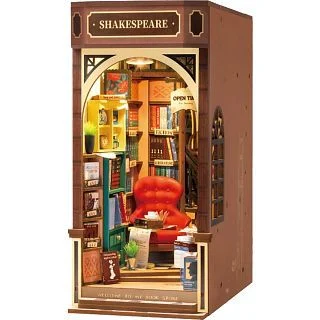 The image features a miniature diorama of a Shakespeare storefront with mini books, a chair, and magazines.