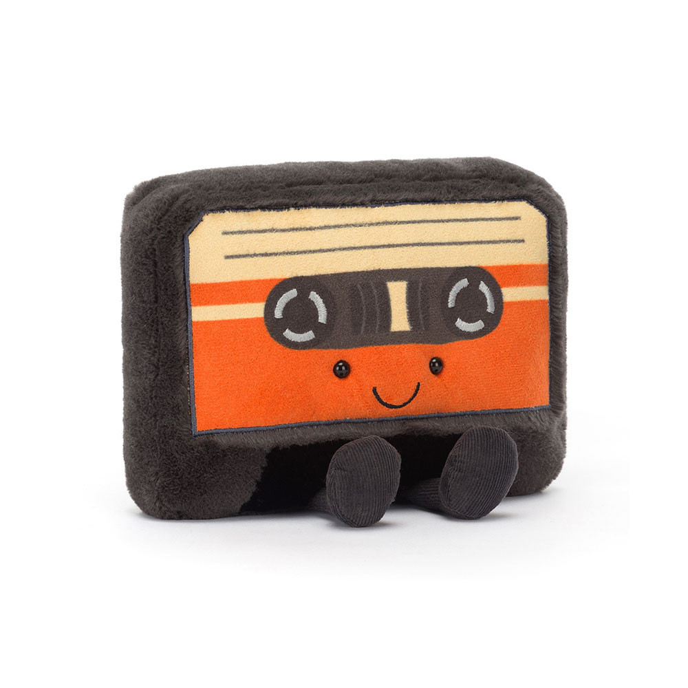 A plush toy shaped like a retro cassette tape with a cheerful face. It has a soft, fuzzy texture with an orange and black design.