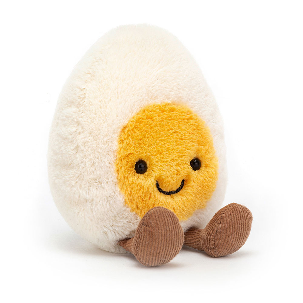 Plush toy shaped like a fried egg with a yellow yolk face, black eyes, and a smile. Brown feet add a playful touch.