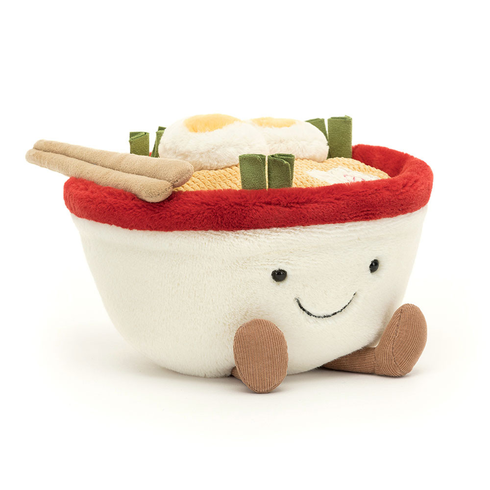 Plush ramen bowl toy with embroidered smile, featuring soft noodles, boiled eggs, and chopsticks. The bowl is white with a red rim and a cute expression.