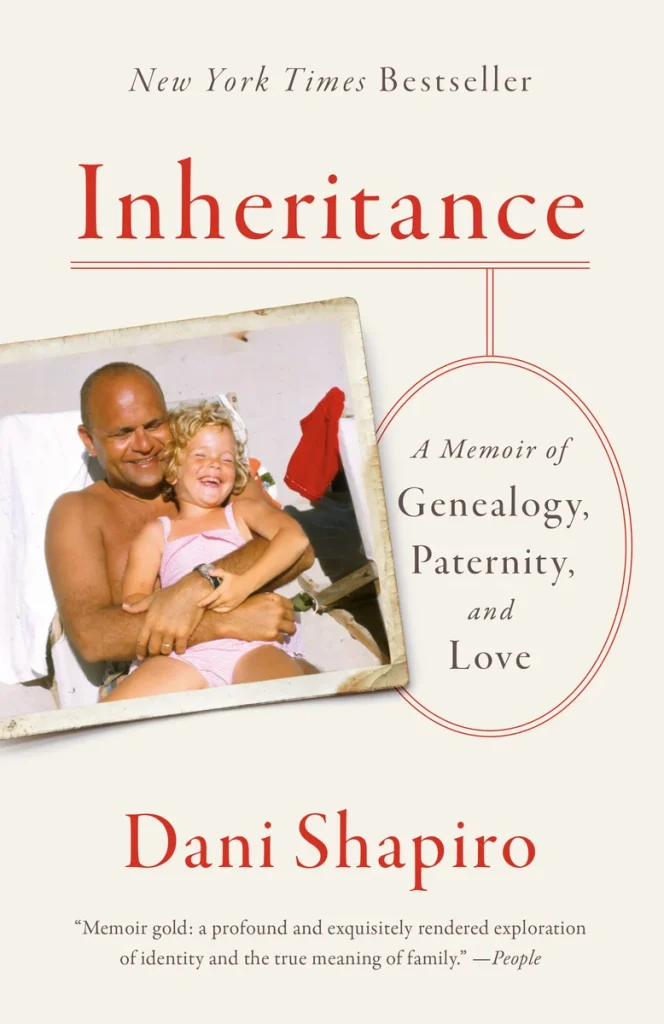 Inheritance by Dani Shapiro book cover depicts a small photo of a young girl sitting on a man's lap on the beach.