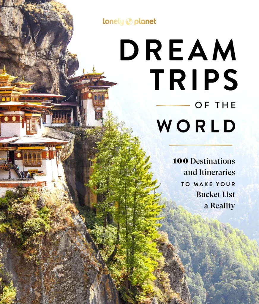 Lonely Planet Dream Trips of the World by Lonely Planet features the side of a mountain with two hotels and trees. The title is placed over another mountain next to it.