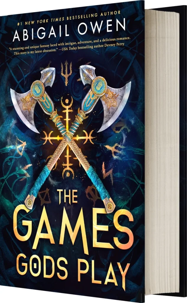 "The Games Gods Play" by Abigail Owen, an epic fantasy book cover featuring two crossed blue and gold axes over glowing mystical symbols on a dark background.