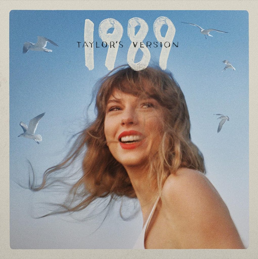 The album cover for 1989 (Taylor's Version) by Taylor Swift. Taylor Swift wears red lipstick and a white tank top and smiles while looking over her shoulder. Behind her is a blue sky featuring flying seagulls.