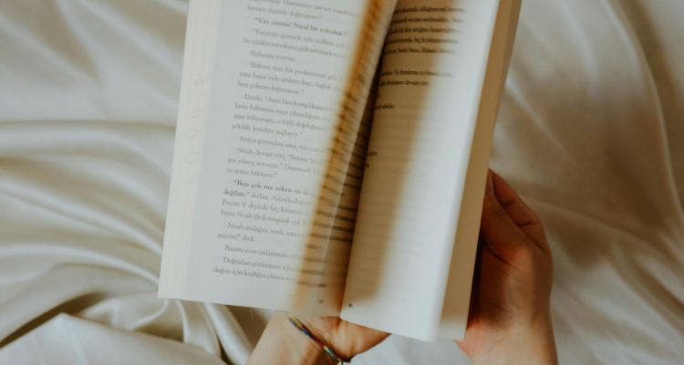handing flipping through a book on cream colored sheets