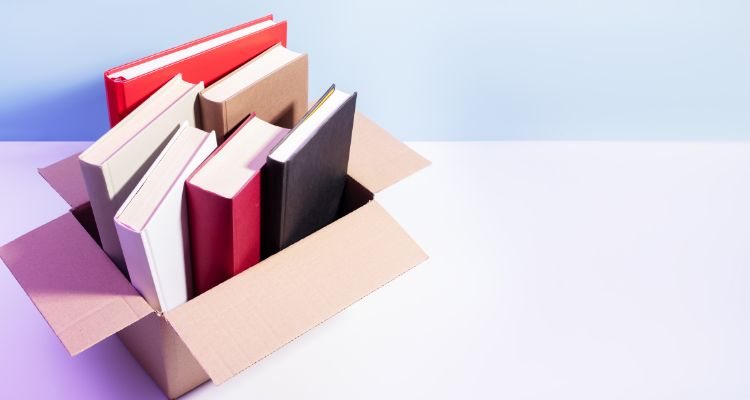This image features books stacked together in an open box on a table.