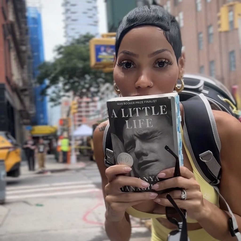 Bookstagrammer Ashley holding “A Little Life” by Hanya Yanagihara while standing on a city street.